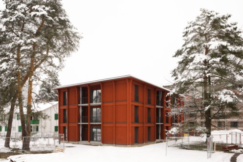 winterlicher Blick auf einen der Neubauten in rotem Holz.